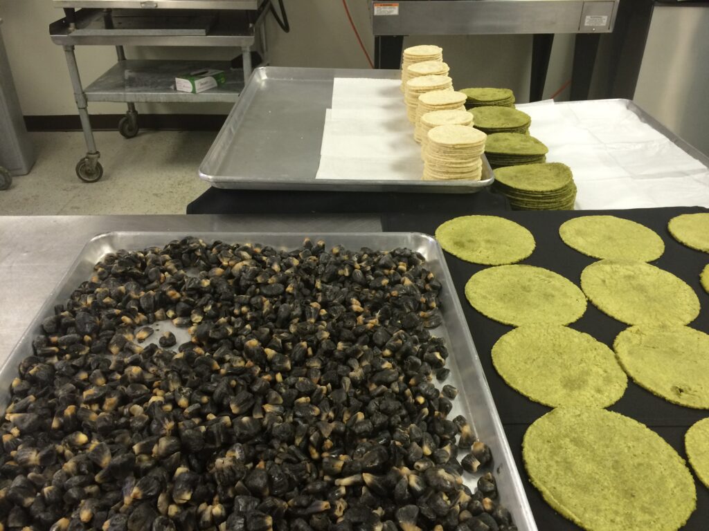 Trays of fresh corn tortillas and roasted chiles at Machete