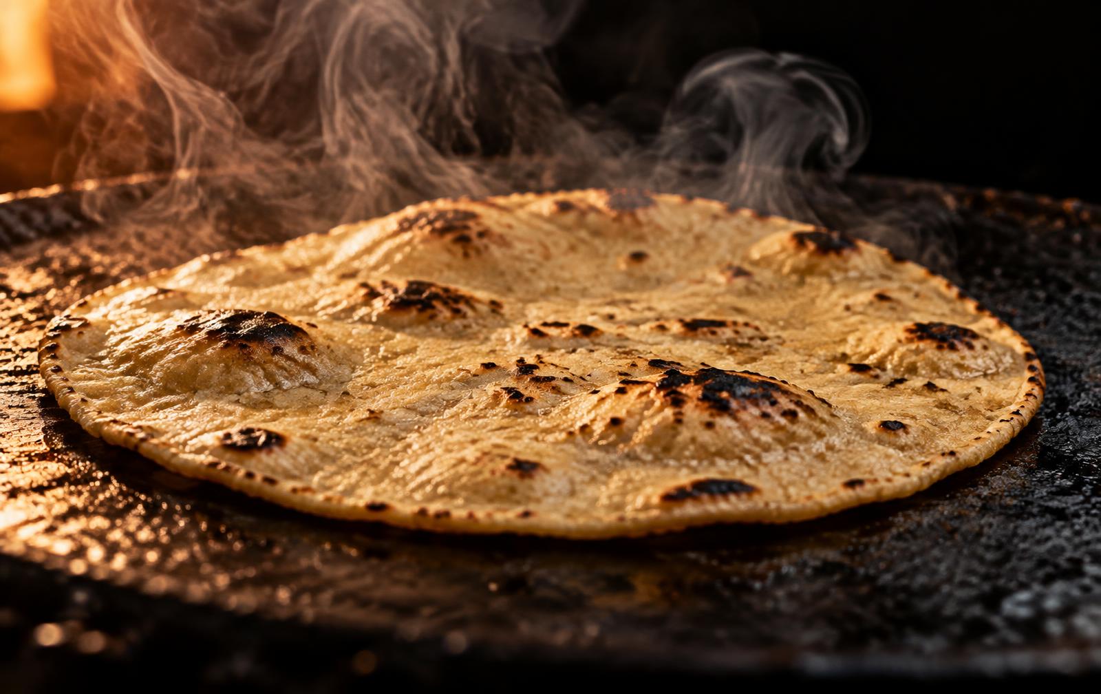 A hand-pressed corn tortilla charring on a hot comal